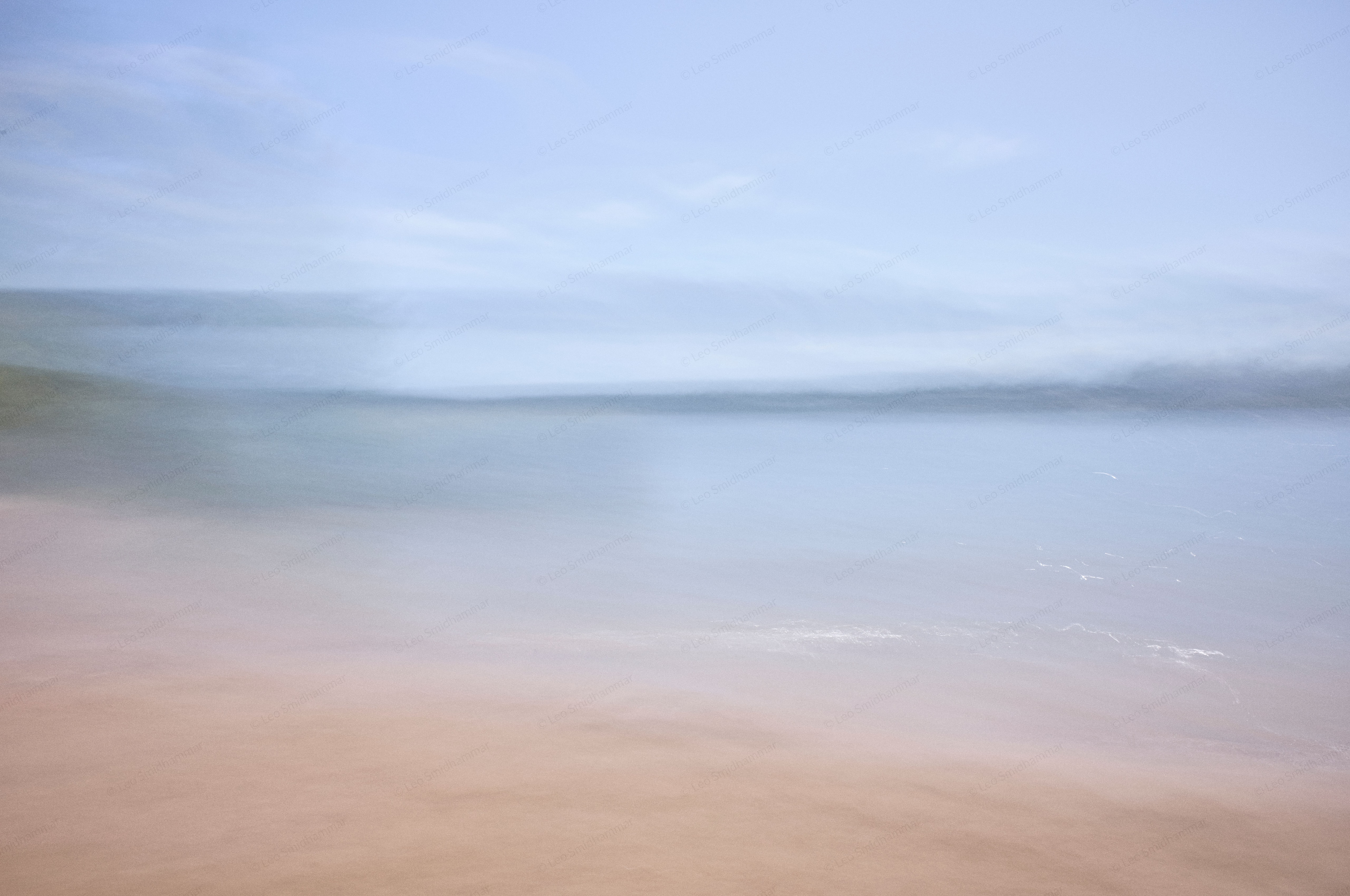 A softly blurred seascape with a pale blue horizon and a pink-toned shoreline.